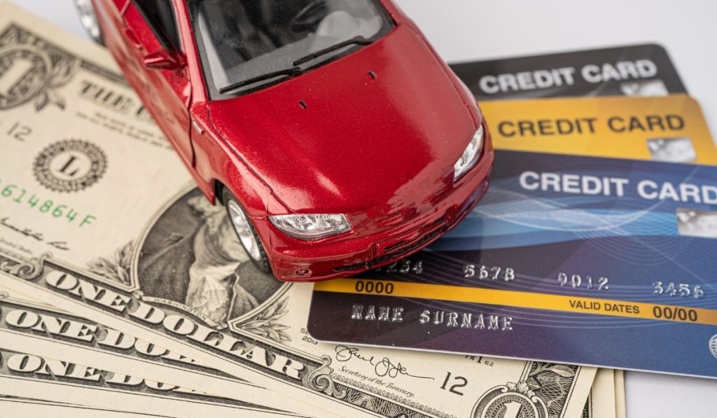 Toy car sitting on credit cards and cash